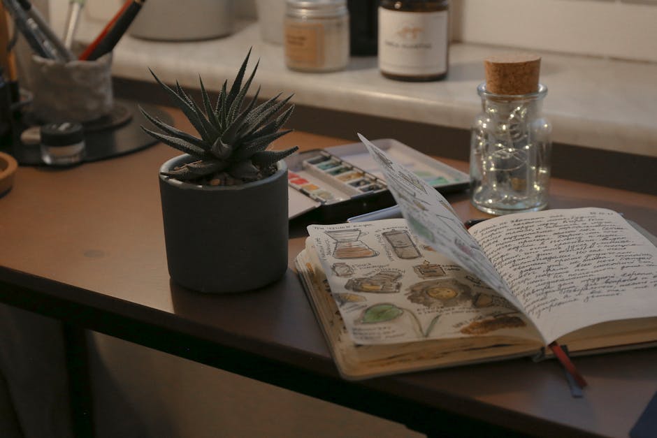 A warm, creative desk setup featuring a sketchbook, succulent, and artistic supplies, perfect for inspiration.